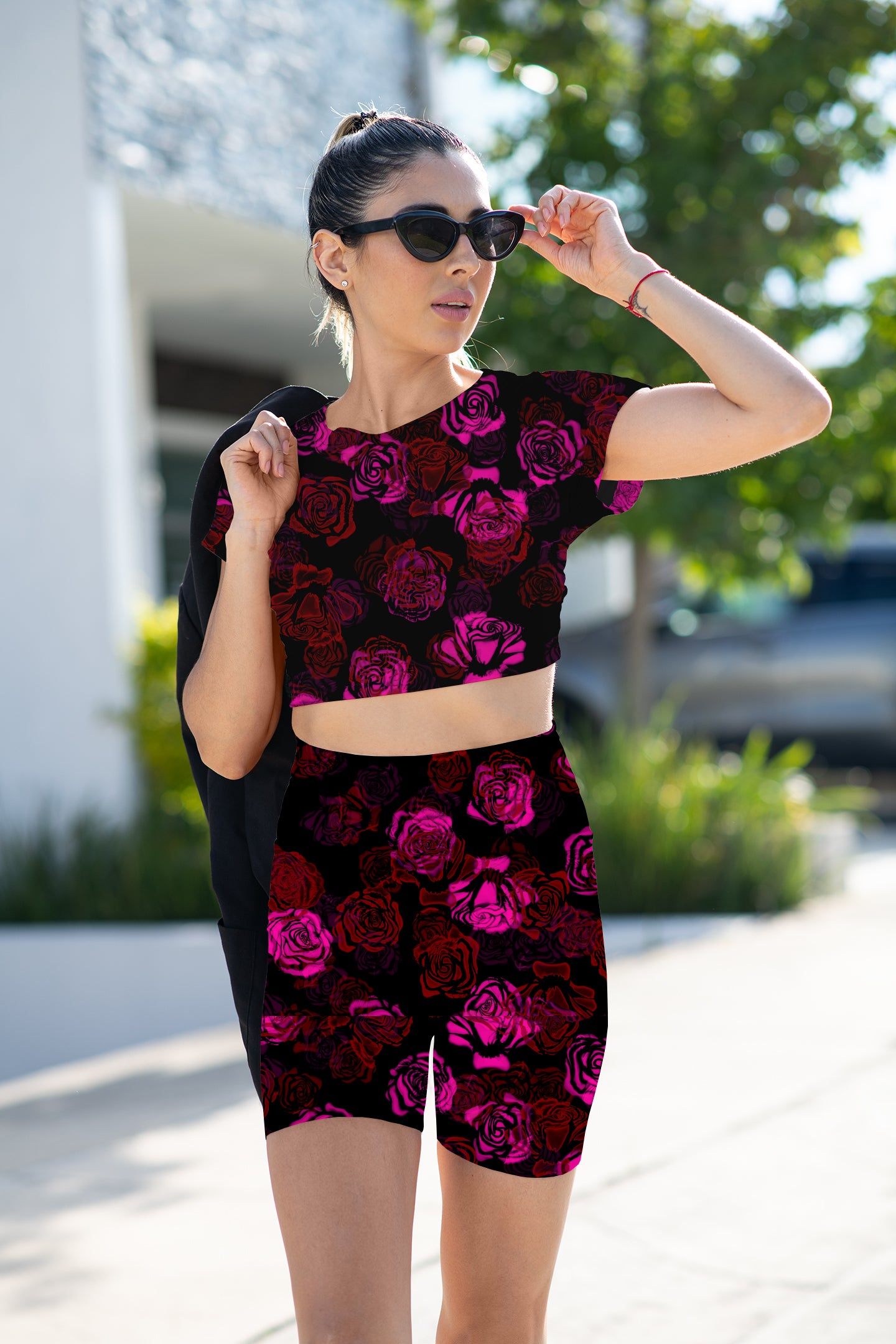 Woman wearing a black and pink floral outfit outdoors. dark floral, rose pattern, seamless print, digital download, floral design, black floral, moody floral, elegant floral, romantic print, abstract roses, gothic floral, vintage rose, botanical print, fabric printing, clothing design, accessories, homeware design, print on demand, textile design, crafts, wallpaper print, 300 dpi, commercial use, high resolution, pink roses, red roses, black background floral, multi colour floral, 10 colour ways, bundle